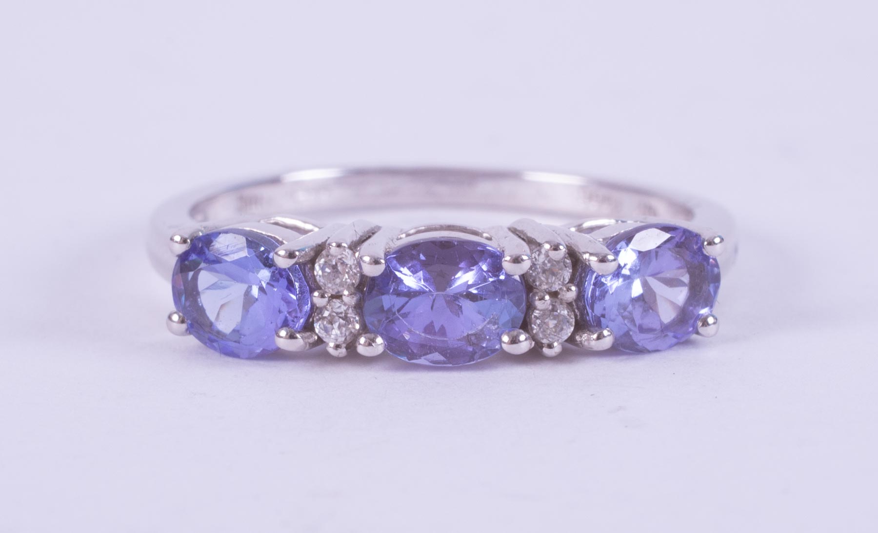 A 9ct white gold ring set with three oval cut tanzanite's interspaced with four small round cut