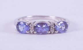 A 9ct white gold ring set with three oval cut tanzanite's interspaced with four small round cut