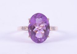 A 9ct yellow gold ring set with an oval cut amethyst, approx. 5.65 carats, with two small round