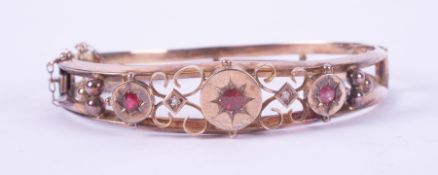 A 9ct yellow gold antique ornately designed bangle set with three round cut red stones & two small