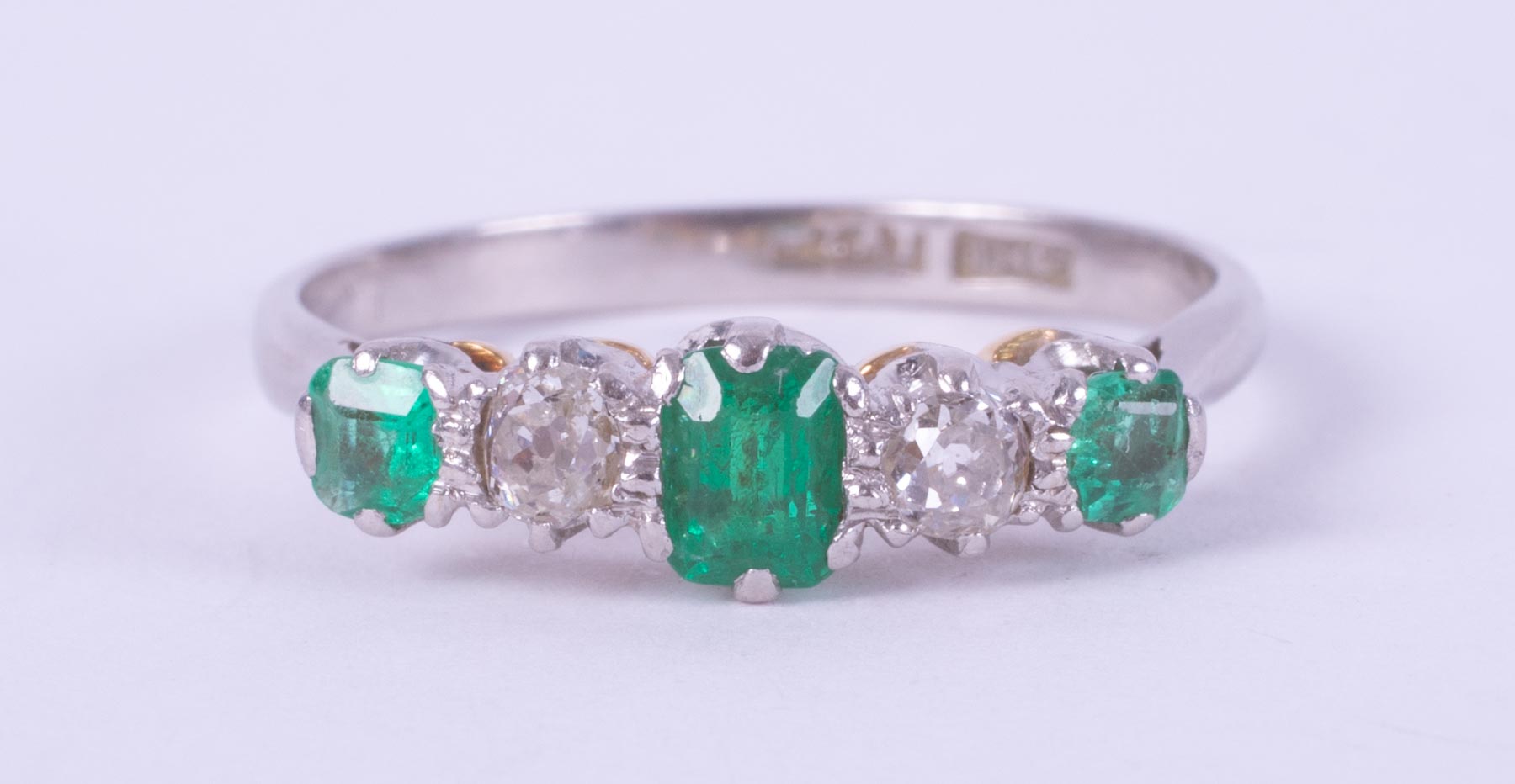 A platinum & 18ct yellow gold five stone ring set with a central emerald cut emerald,