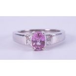An 18ct white gold ring set with an oval cut pink sapphire, approx. 0.77 carats with two princess