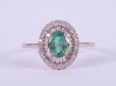 A 9ct yellow gold halo design ring set with a central oval cut emerald, approx. 0.78 carats,