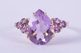 A 9ct yellow gold ring set with a central pear shaped amethyst, approx. 3.75 carats, with a