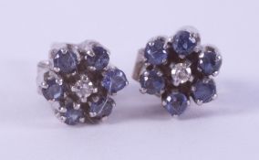 A pair of 18ct white gold flower studs set with small round cut sapphires & a small central diamond,