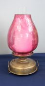 A Victorian oil lamp with a cranberry/pink coloured reservoir with a pink shade, height excluding