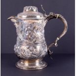 A George III silver lidded flagon/jug with spout, face mask decoration, embossed with flowers,