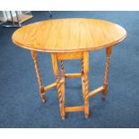 A small light oak drop leaf table with barley twist legs, height 74cm and width 50cm.