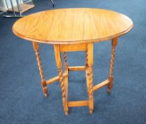 A small light oak drop leaf table with barley twist legs, height 74cm and width 50cm.