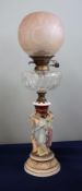 A Victorian oil lamp with glass reservoir and a smokey brown shade with a ceramic three lady base,