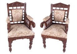 A pair 19th century Anglo Indian style ornately carved hardwood chairs with dragon scroll arms, over