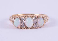 An 18ct yellow gold scroll design ring set with three oval cabochon cut opals interspaced by four