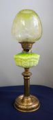 A Victorian oil lamp with a green glass column and a green glass shade decorated with flowers on a