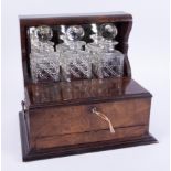 A Victorian mahogany and walnut three bottle tantalus with the front double hinged with lock and