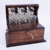 A Victorian mahogany and walnut three bottle tantalus with the front double hinged with lock and