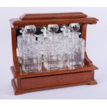 A three bottle tantalus in hardwood cabinet.
