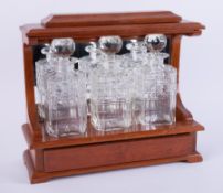 A three bottle tantalus in hardwood cabinet.