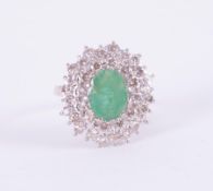 A white gold (no hallmarks & not tested) cluster ring set with a central oval cut emerald, approx.