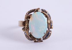 A 14k yellow gold ornately designed ring set with an oval cabochon cut opal, measuring approx. 14.