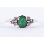 A white gold ring (no hallmarks & not tested) set with a central oval cut emerald, approx.0.94