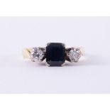 An 18ct yellow & white gold three stone ring set with a central emerald cut sapphire, approx.0.75