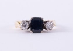 An 18ct yellow & white gold three stone ring set with a central emerald cut sapphire, approx.0.75