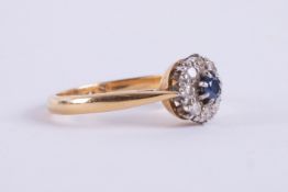 An 18ct yellow & white gold cluster ring set with a central round cut sapphire and surrounded by