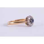 An 18ct yellow & white gold cluster ring set with a central round cut sapphire and surrounded by