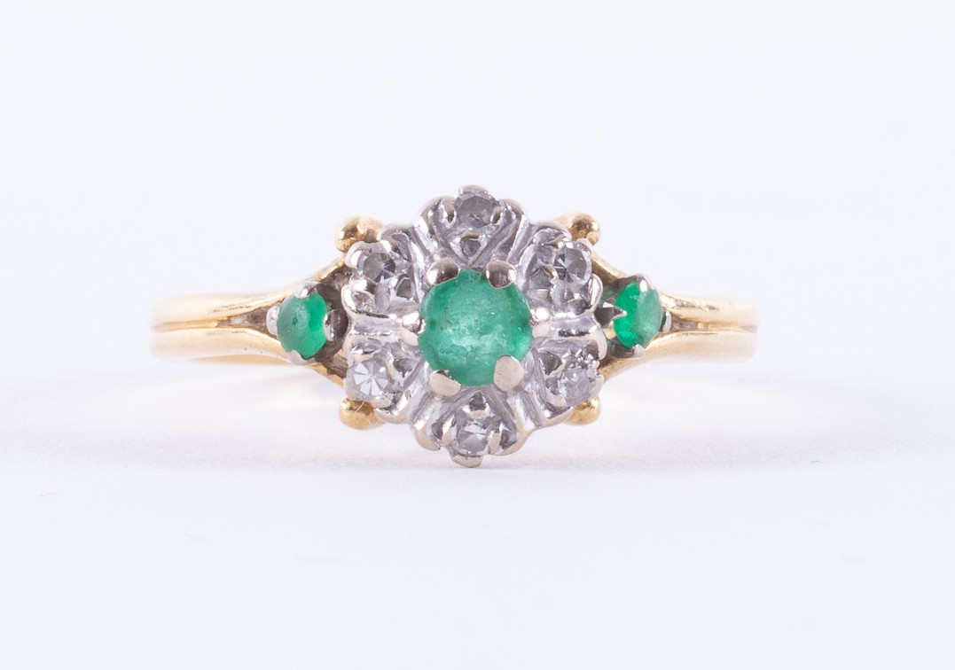 An 18ct yellow & white gold cluster design ring set with three round cut emeralds, approx. total