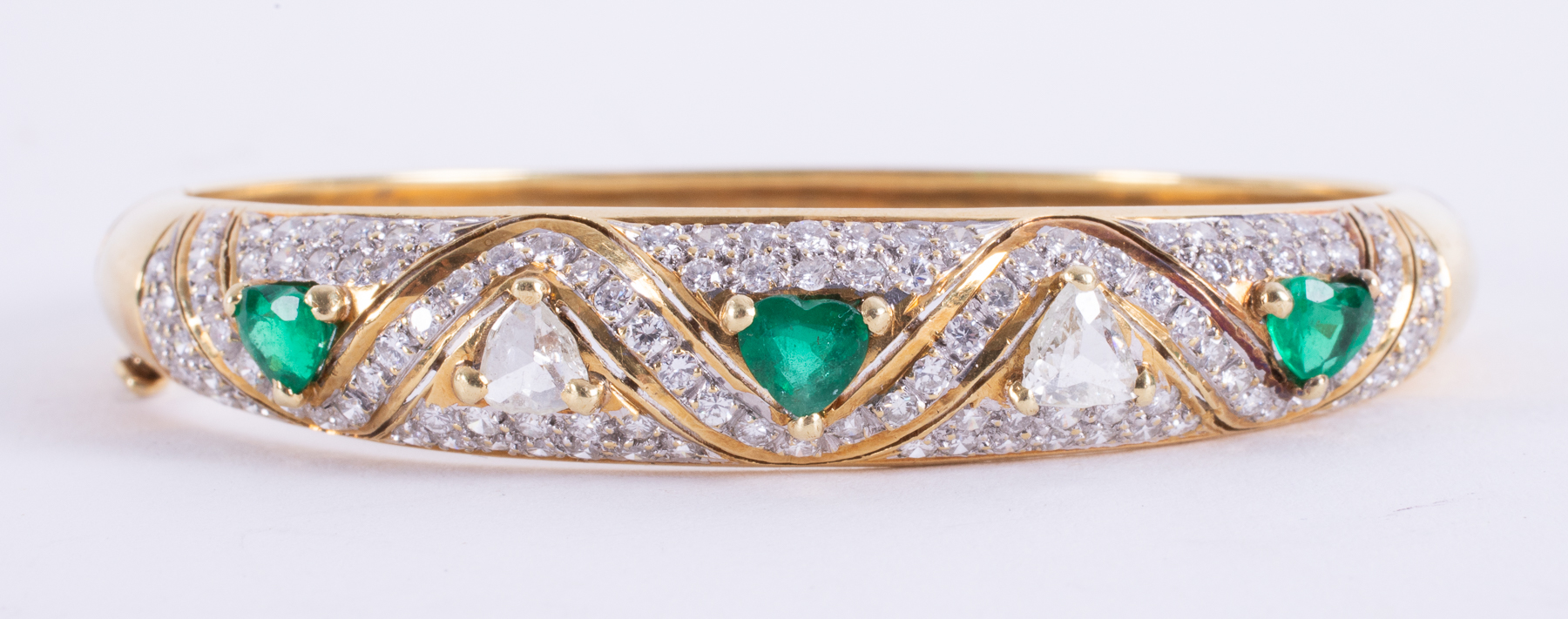 An impressive 18ct yellow gold bangle set with three heart shaped emeralds, approx.