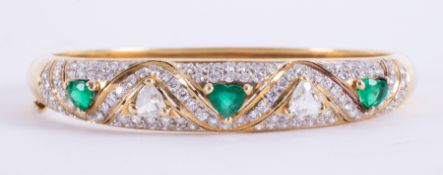 An impressive 18ct yellow gold bangle set with three heart shaped emeralds, approx.