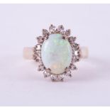 A 14ct yellow gold cluster ring set with a central cabochon cut opal, measuring approx. 11mm x 8.5mm