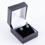 A pair of 10k white & yellow gold flower cluster earrings set with round cut emeralds, total emerald