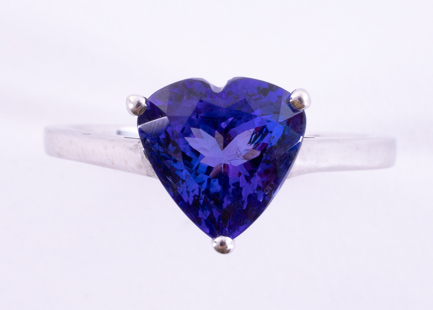 An impressive white gold ring set with a fine heart shaped intense violet blue tanzanite,