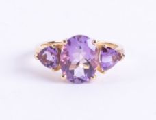 A 9ct yellow gold ring set with a central oval cut amethyst with a triangular cut amethyst to each