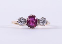 An 18ct yellow & white gold three stone ring set with a central oval cut ruby, approx. 0.42