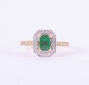 A fine 18ct yellow gold & platinum 'halo' design ring set with a central emerald cut emerald,