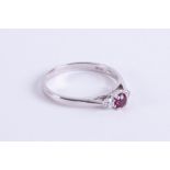 An 18ct white gold three stone ring set with a central round cut ruby, approx. 0.23 carats with a