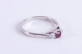 An 18ct white gold three stone ring set with a central round cut ruby, approx. 0.23 carats with a