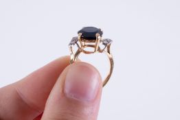 A yellow gold ring (not hallmarked or tested), set with a central round cut dark blue sapphire,