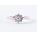 An 18ct white gold flower cluster style ring set with a central round brilliant cut diamond, approx.