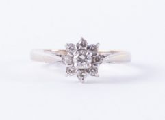 An 18ct white gold flower cluster style ring set with a central round brilliant cut diamond, approx.