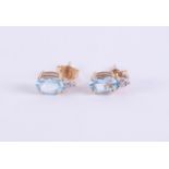 A pair of 9ct yellow gold stud earrings set with an oval cut blue topaz and with a small round cut