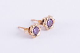 A pair of 9ct yellow gold flower studs set with a round cut purple stone, 6mm diameter, post &