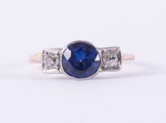 An antique 18ct yellow gold & platinum three stone ring set with a central round cut sapphire,