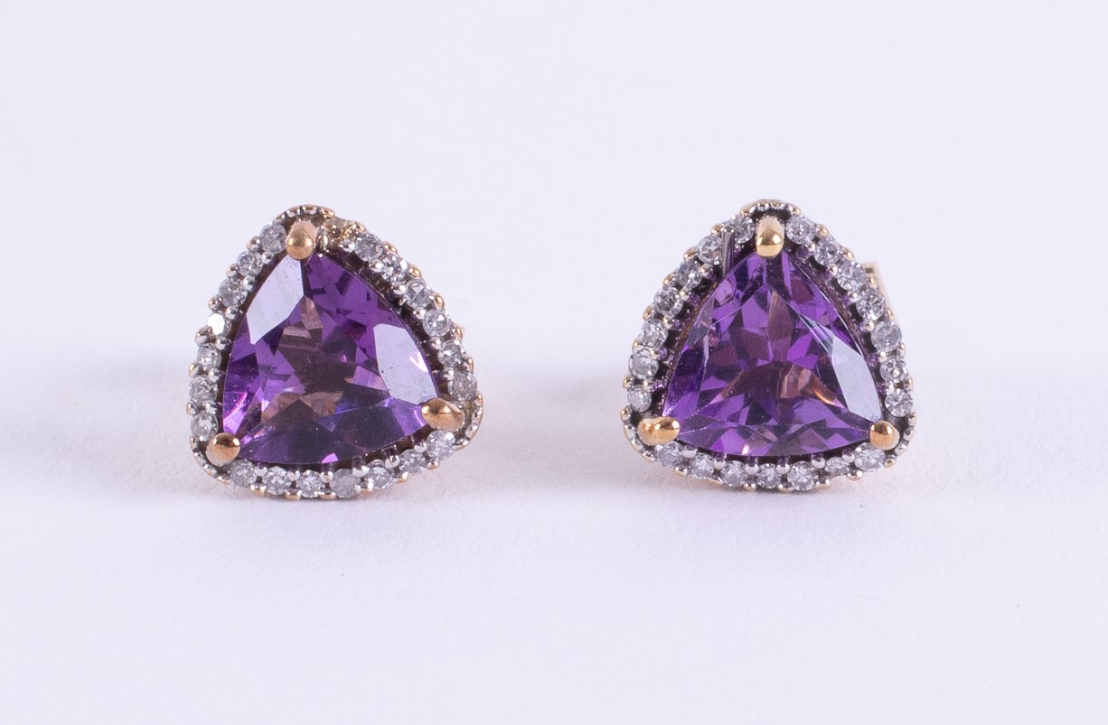 A pair of 9ct yellow gold stud earrings set with a triangular shaped amethyst and surrounded by tiny