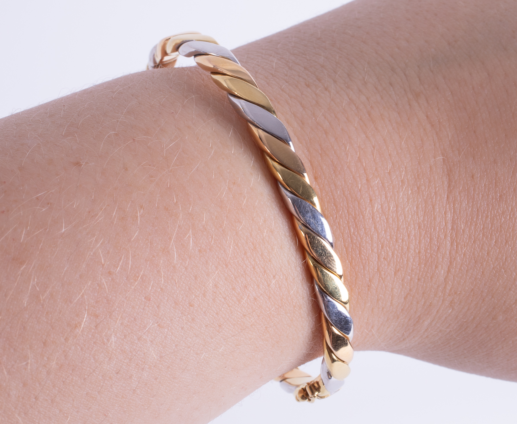 An 18ct yellow, white & rose gold twist design hinged bangle with push in clasp & figure of eight