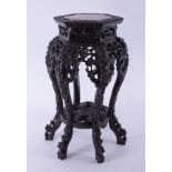 A Chinese carved hardwood table inset with a pink marble, height 61cm.