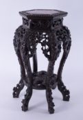 A Chinese carved hardwood table inset with a pink marble, height 61cm.
