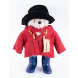 A large Paddington bear with red coat and blue wellingtons.
